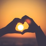 hands in heart around sun